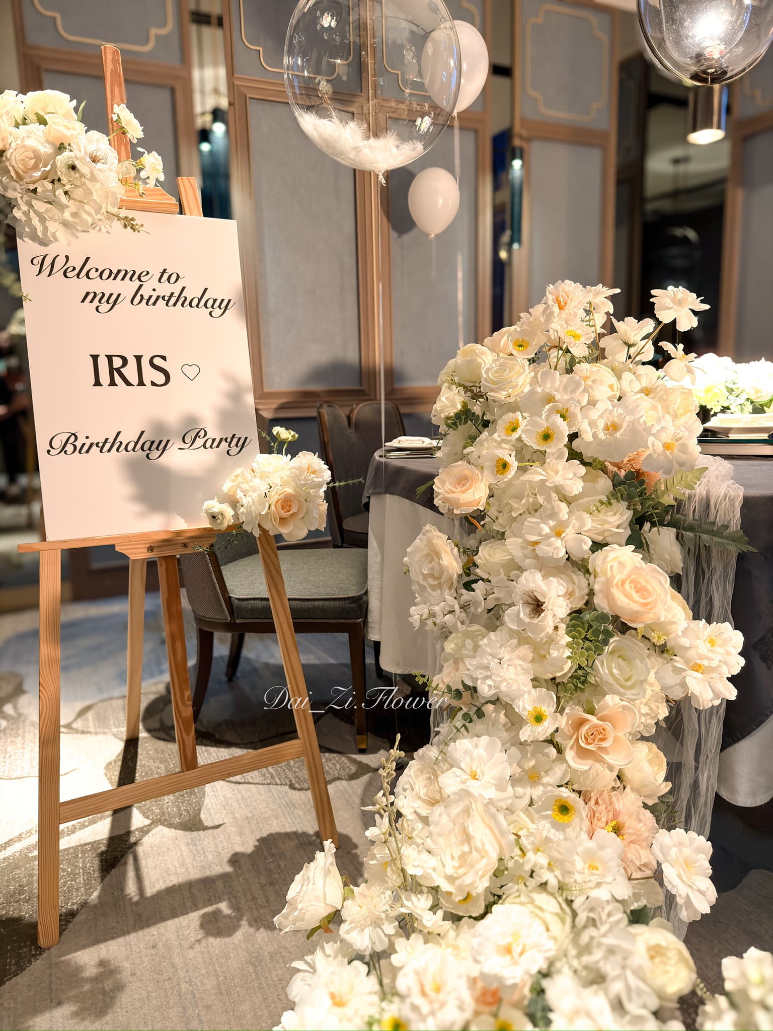 客製化迎賓背板細節，寫有 Welcome to my birthday IRIS，搭配香檳色系精品花藝。