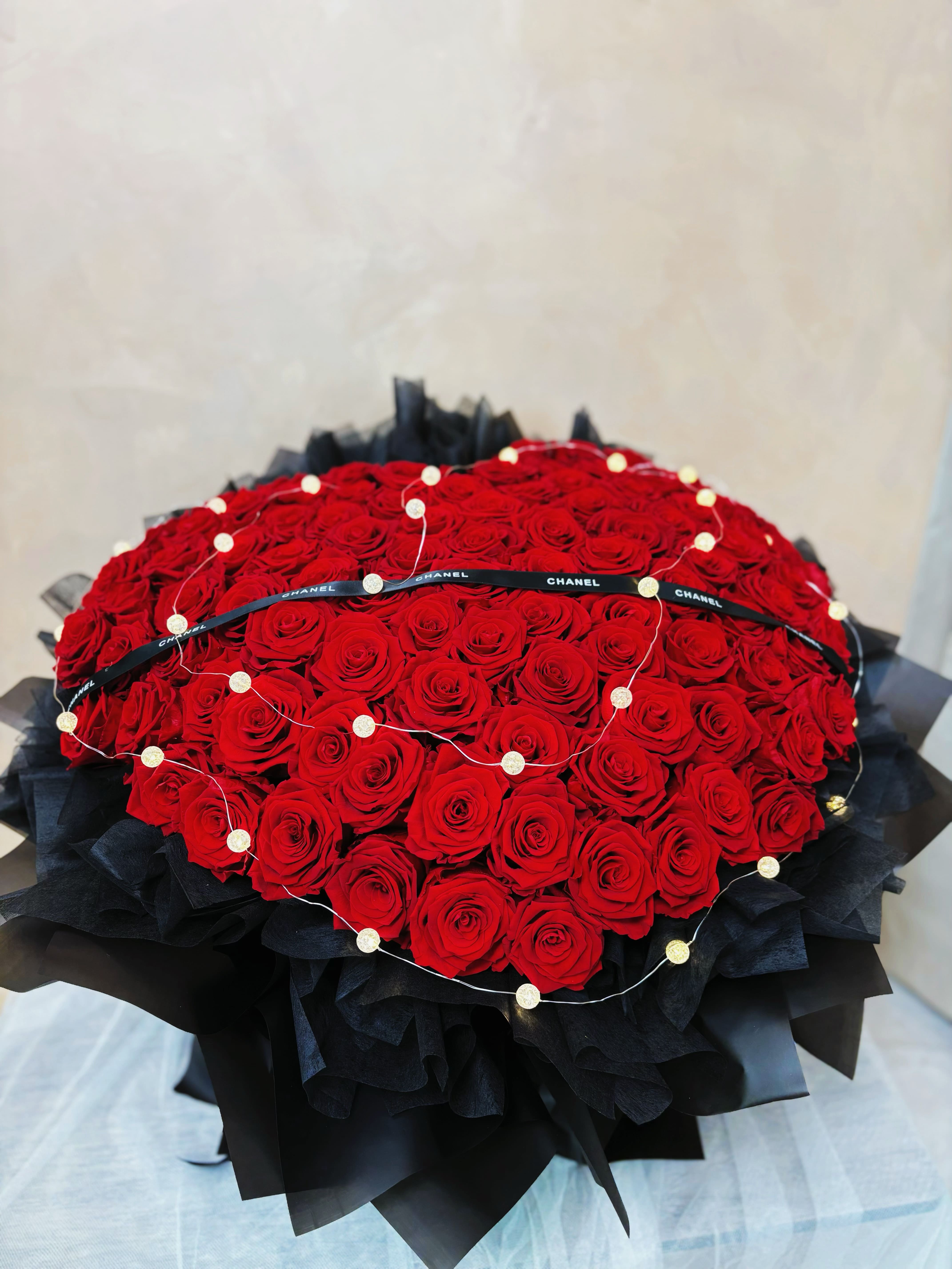 DAIZI代紫花藝-經典黑紅配色心型100朵永生玫瑰花束，結合浪漫燈絲與高質感精品包裝，大台北地區專屬全客製化重大週年紀念與極致寵愛送禮首選。