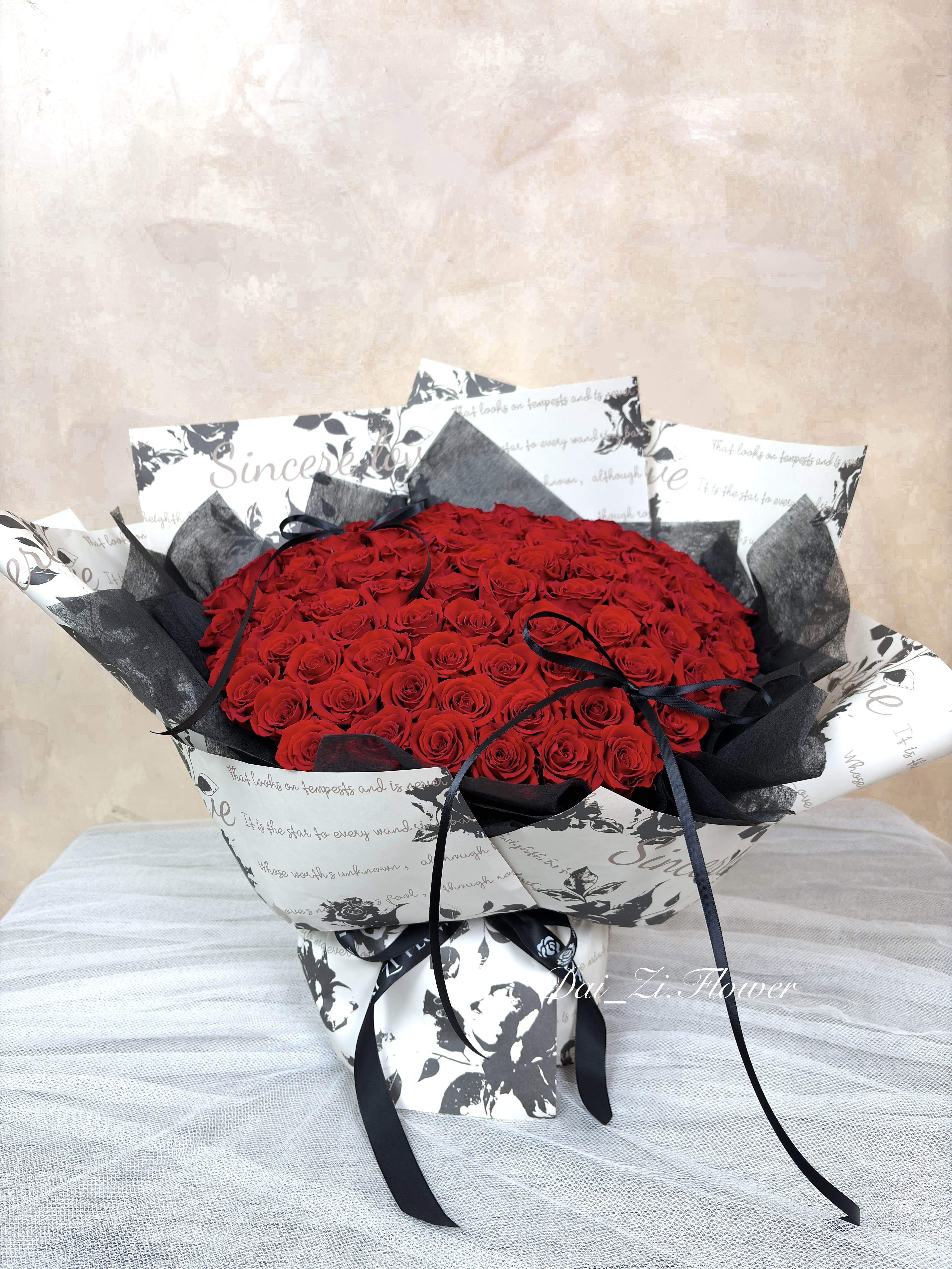 DAIZI代紫花藝-經典黑紅配色100朵紅永生花束展示，巨大份量感象徵百分之百的愛與承諾，大台北地區提供全客製化精品情人節與求婚送禮方案。