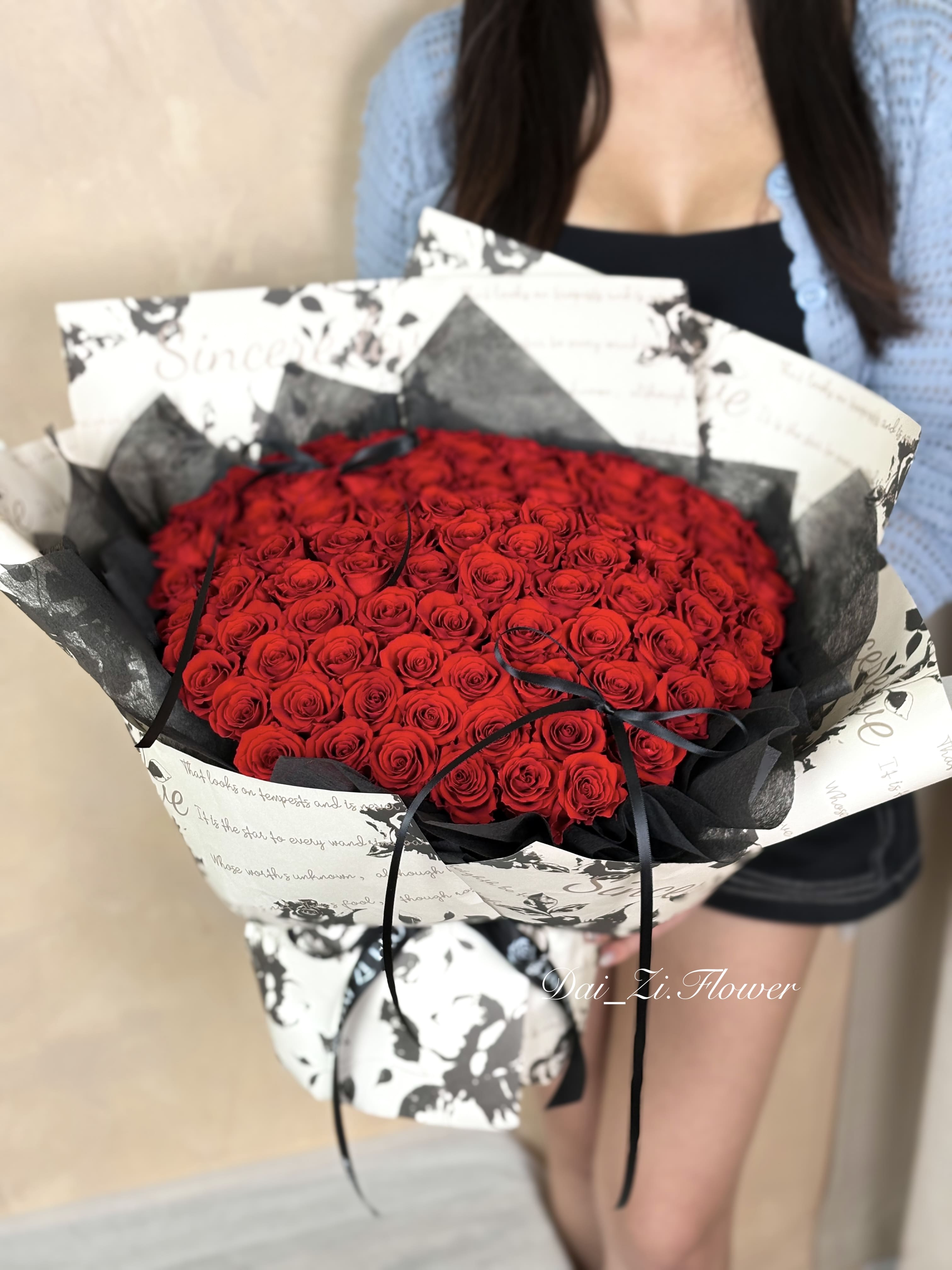 DAIZI代紫花藝-手持巨型100朵紅永生花束實拍，搭配質感黑白時尚包裝與專屬黑色緞帶，大台北地區客製化求婚花束與極致告白送禮推薦。