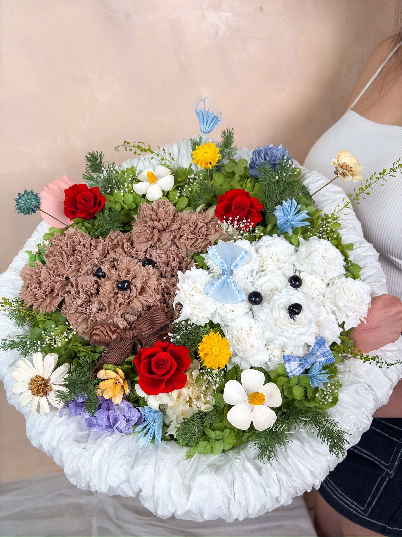 DAIZI代紫花藝-手持創意永生小狗花束實拍，精緻還原棕白雙色狗狗造型，搭配草原系綠葉與紅玫瑰，大台北地區客製化寵物主題花禮與生日驚喜首選。