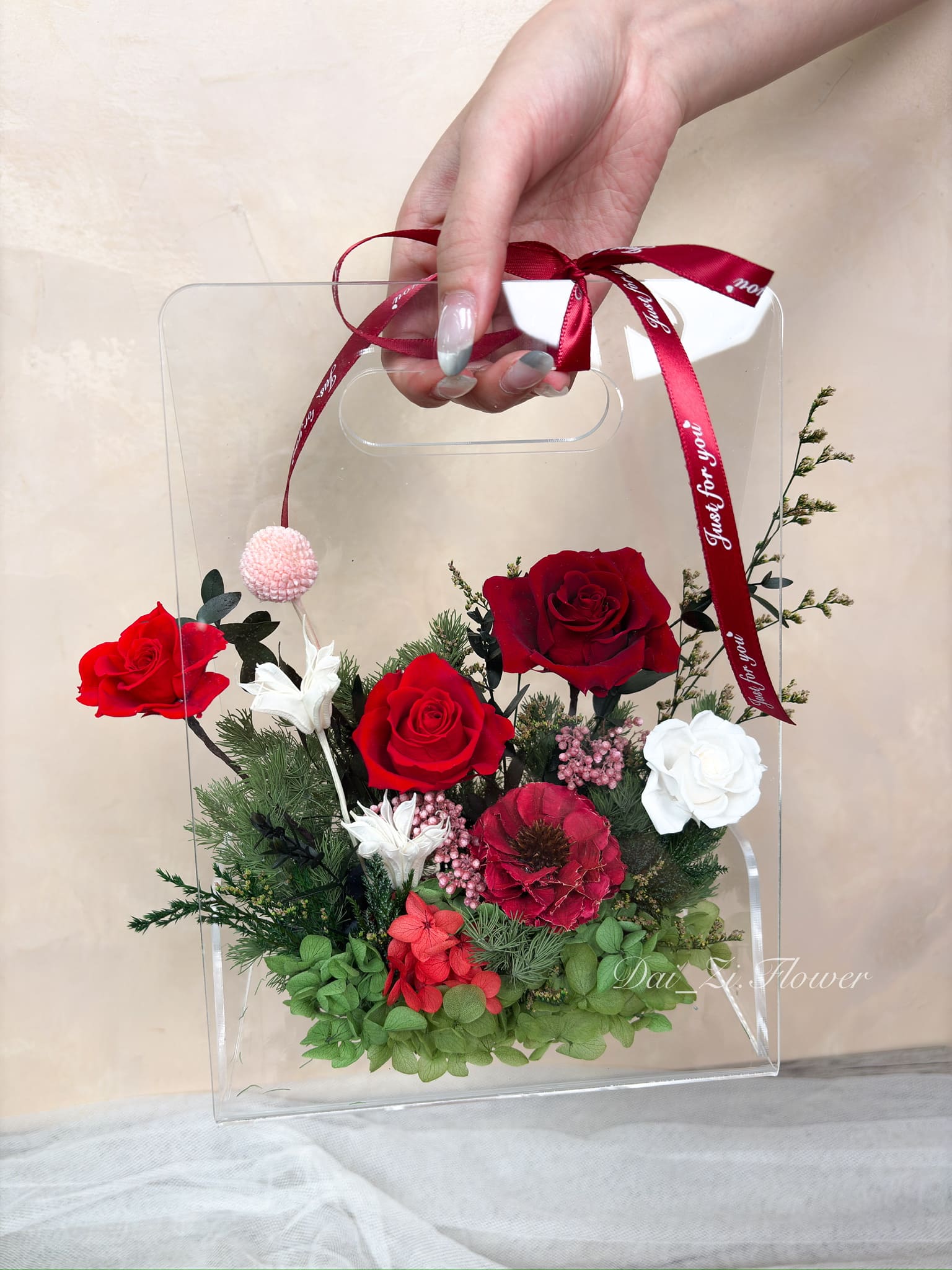 手提質感紅、白、綠色系永生花透明提盒展示，唯美精品花藝搭配質感紅色緞帶，展現極致浪漫氛圍，DAIZI代紫花藝為大台北地區打造的高級客製化驚喜花禮。