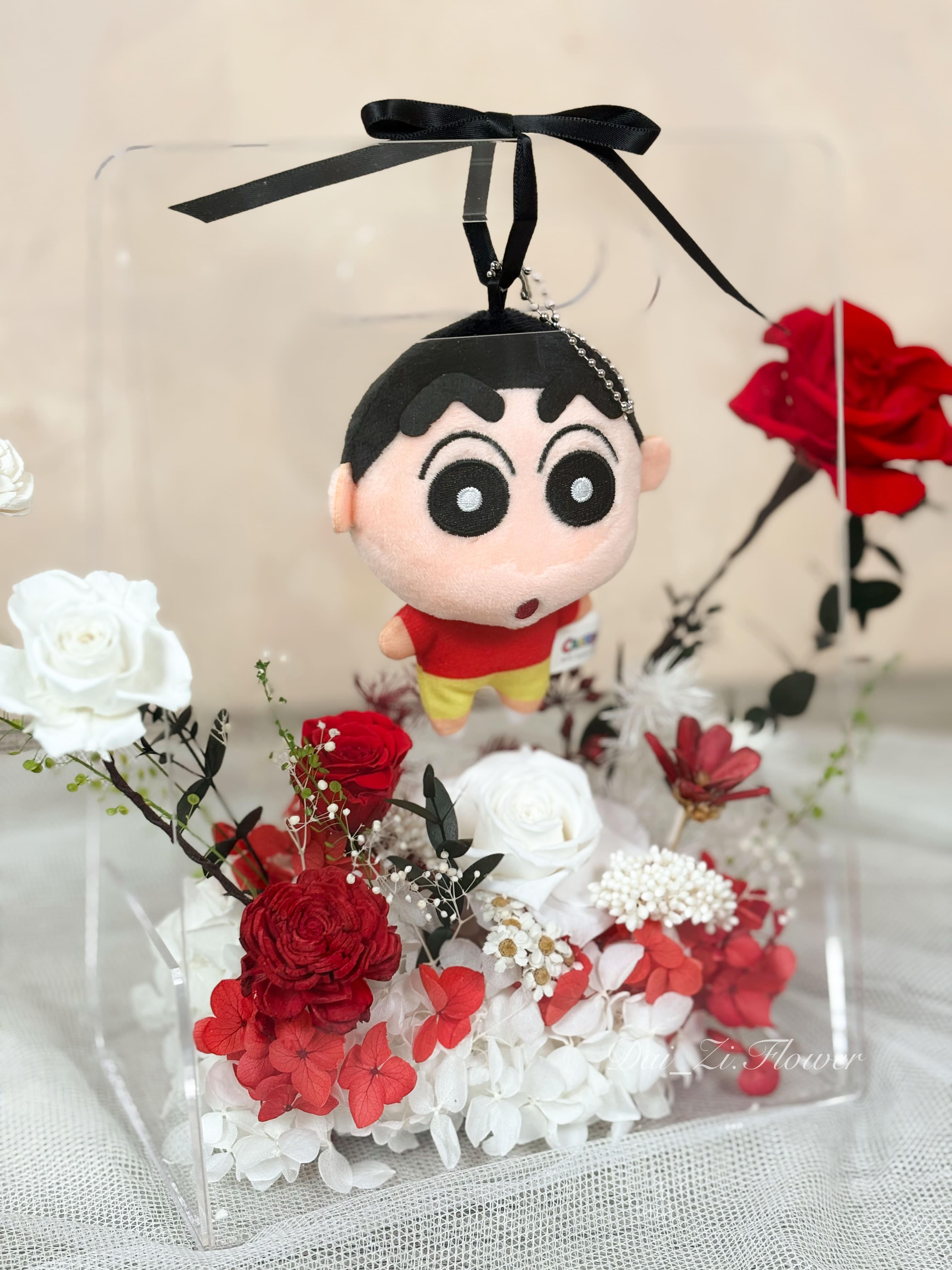 質感紅、白色系永生花透明提盒近觀特寫，結合超萌蠟筆小新娃娃與頂級紅玫瑰，展現極致浪漫與童趣氛圍，DAIZI代紫花藝專為大台北地區打造的全客製化流行IP精品送禮。