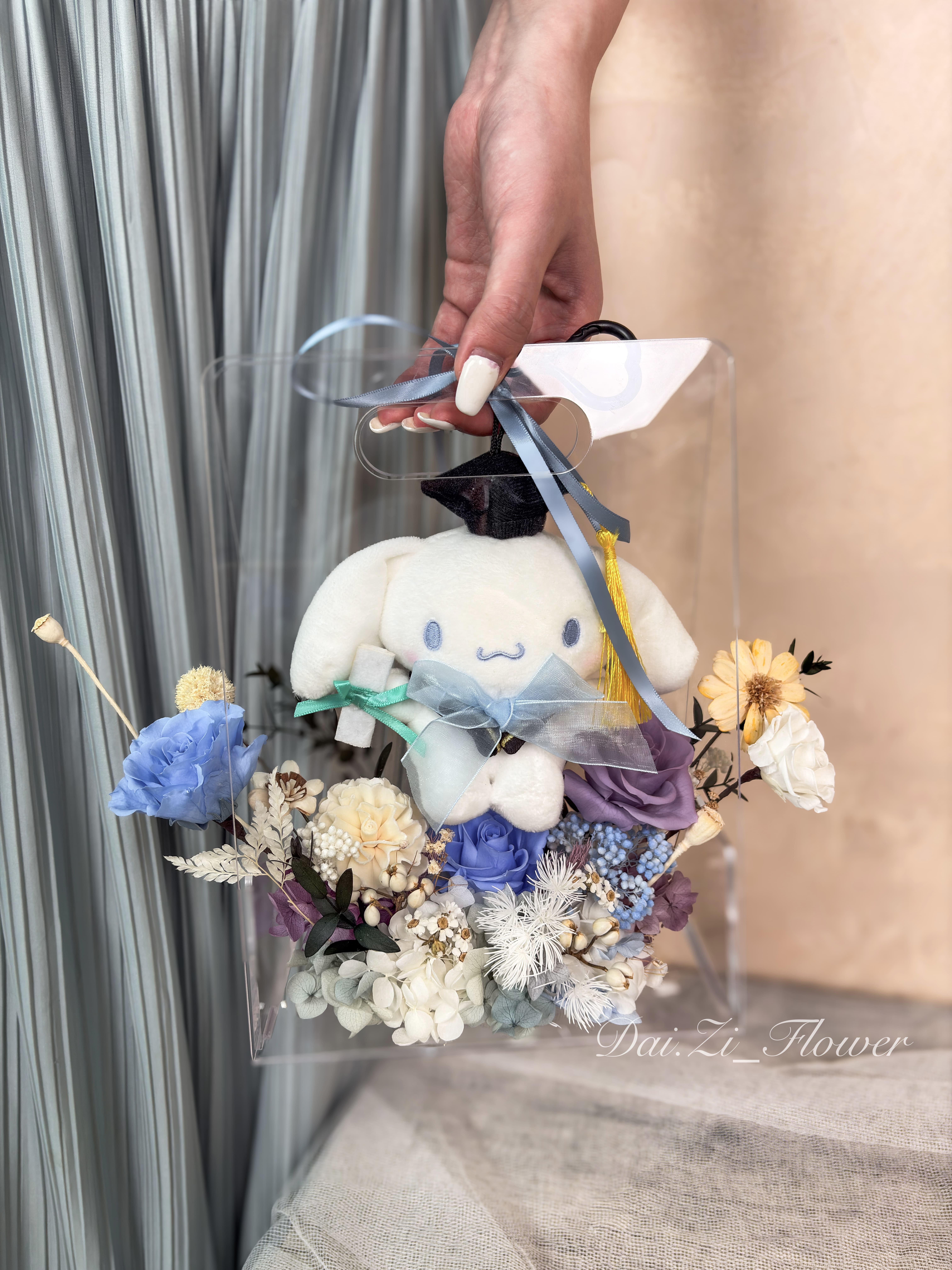 手提質感大耳狗娃娃與藍、紫色系永生花提盒展示，唯美精品花藝設計搭配夢幻透明質感包裝，展現極致仙氣氛圍，大台北地區提供全客製化精品送禮方案推薦DAIZI代紫花藝。