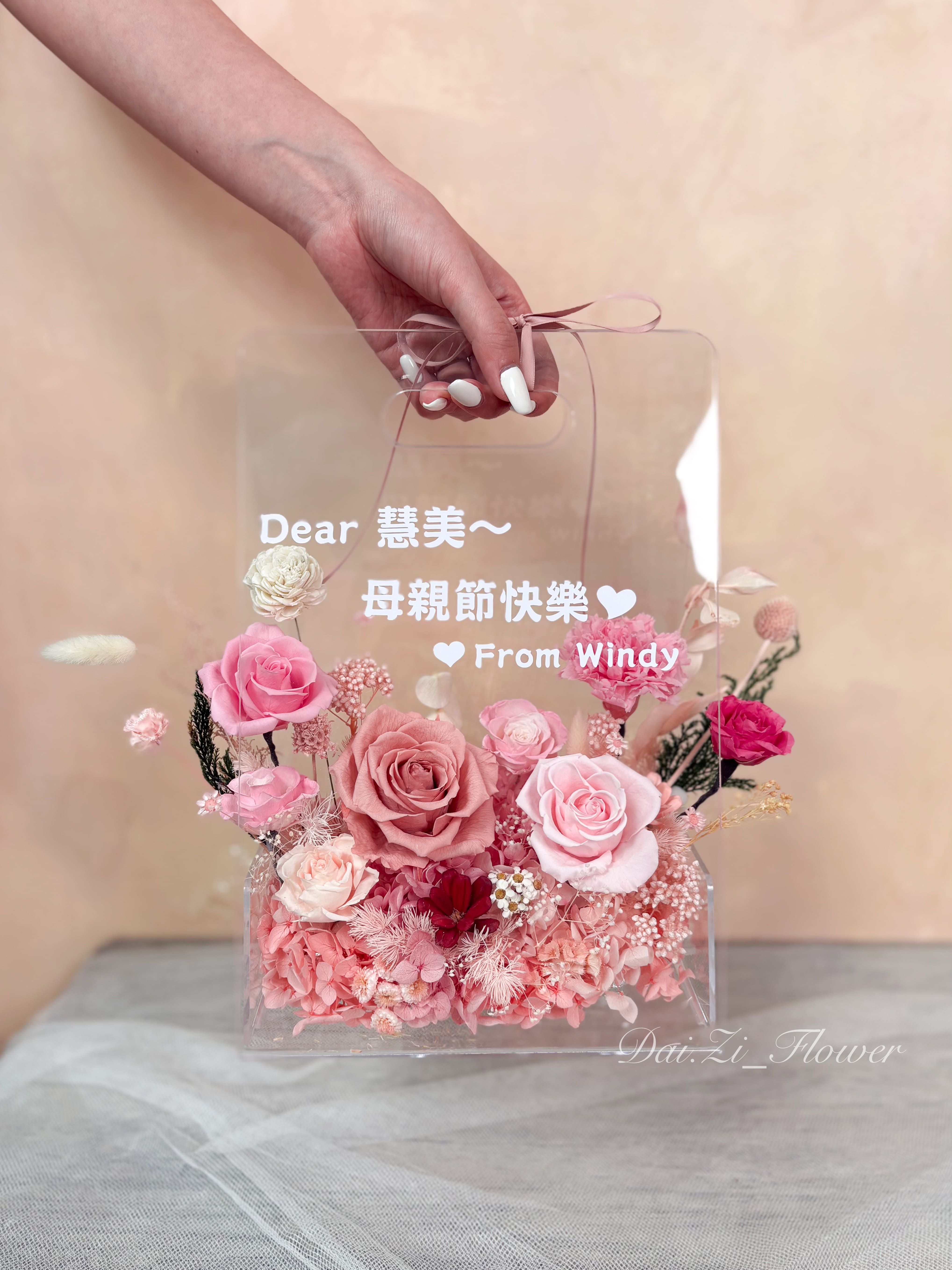 手提質感粉色系永生花玫瑰與康乃馨提盒展示,透明包裝搭配專屬客製化母親節祝福文字,DAIZI代紫花藝專為大台北地區打造的頂級精品花禮。