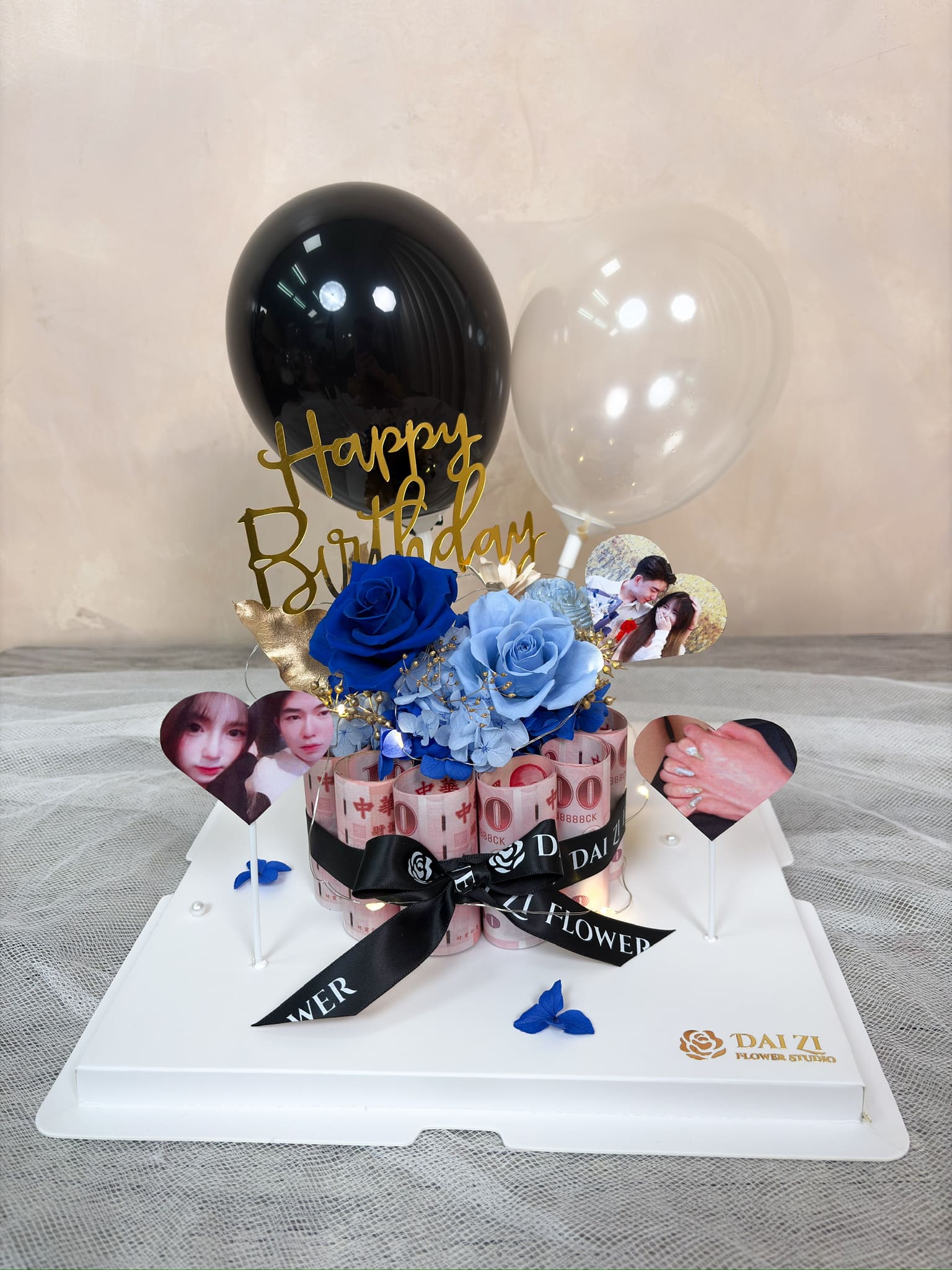 大台北高質感花店 DAIZI代紫花藝專屬客製化生日驚喜，結合頂級深淺藍色系永生玫瑰與客製化情侶照片，打造絕美永生花鈔票蛋糕，搭配黑白雙色氣球與有錢花設計，是給另一半最完美的浪漫禮物。