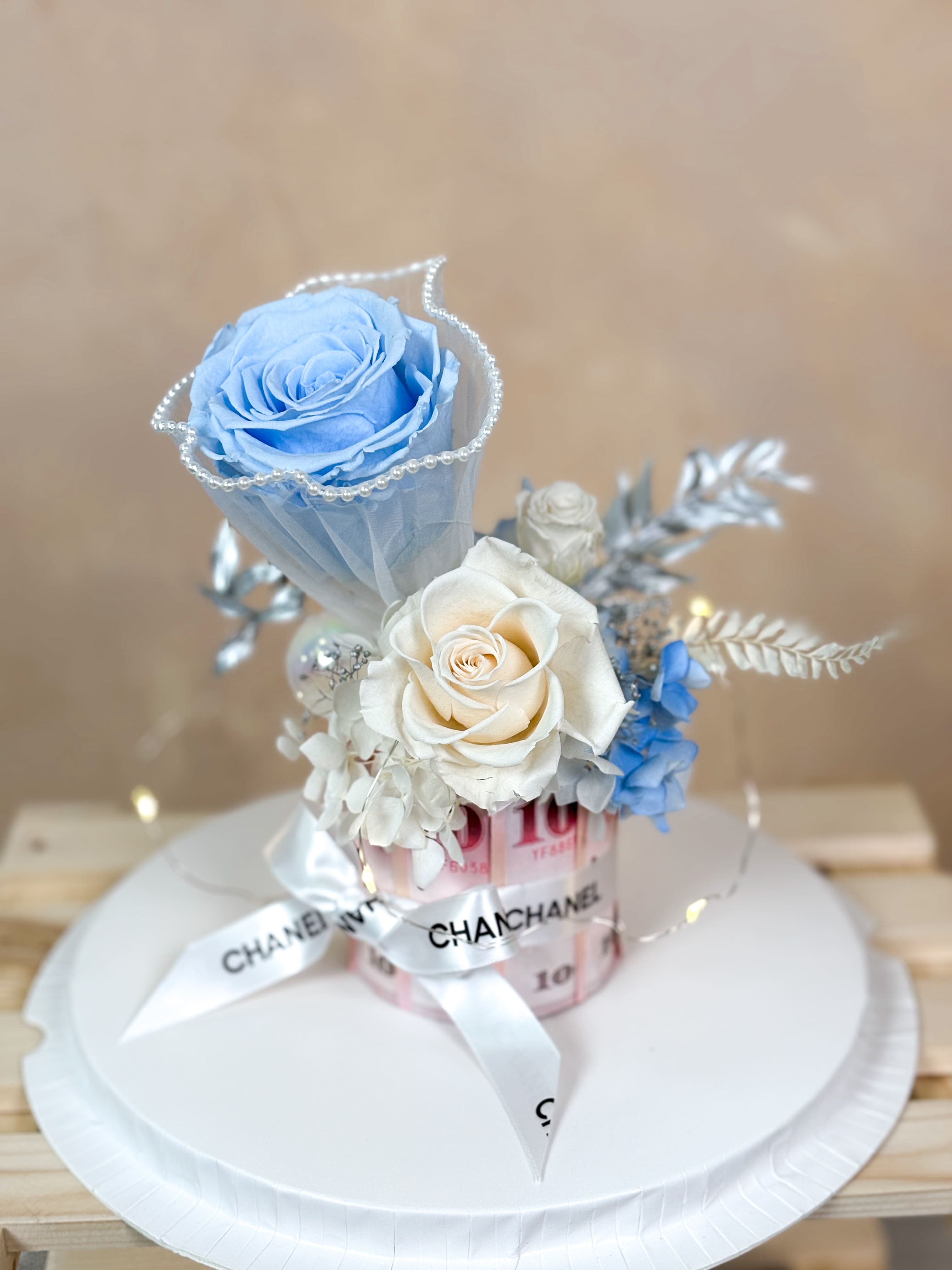 DAIZI代紫花藝清新藍白系永生花鈔票蛋糕，以精品緞帶妝點真實鈔票設計之有錢花，搭配優雅藍玫瑰與珍珠裝飾，是精緻且獨特的客製化浪漫禮物。