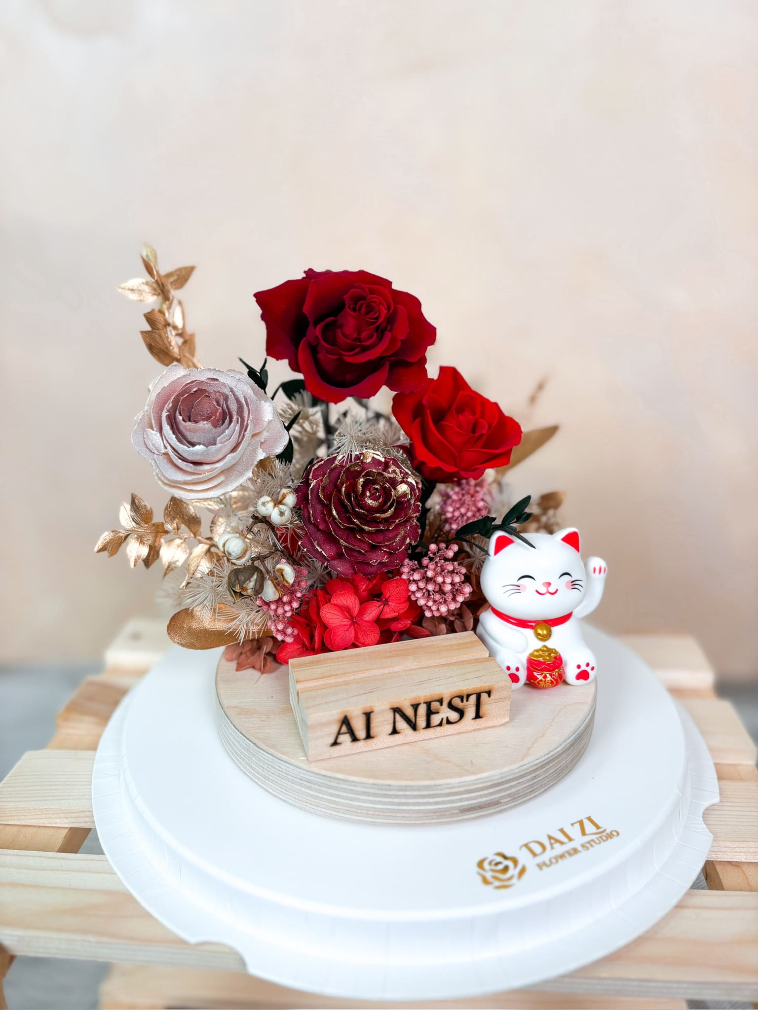 客製化永生花名片座細節特寫，代紫花藝嚴選紅玫瑰、金葉與木質名片架，搭配吸睛招財貓，展現最體面且具備品牌辨識度的開幕送禮心意。