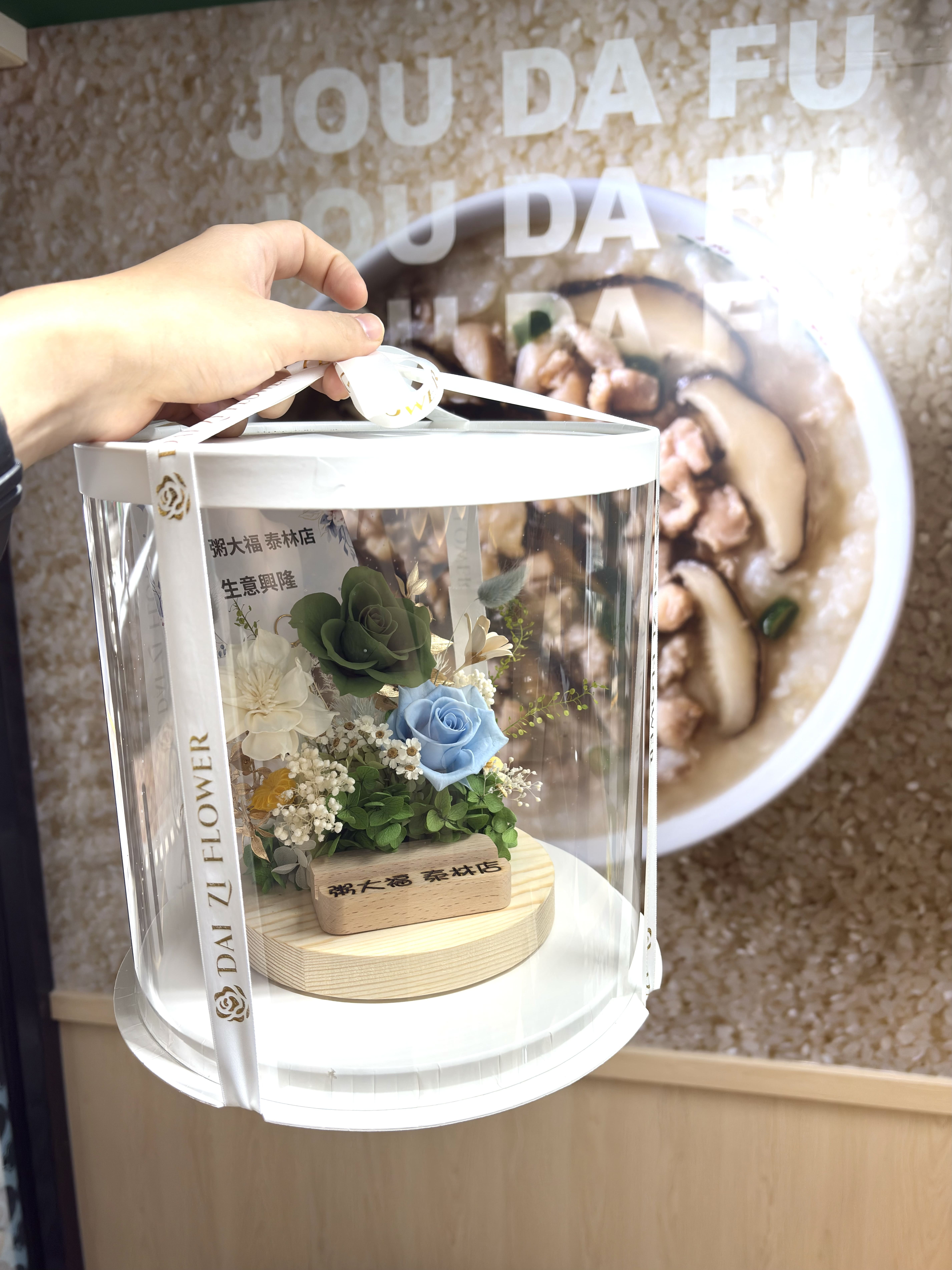 大台北精品客製化開幕花禮，DAIZI 代紫花藝設計之永生花名片座，搭配高質感透明圓形禮盒包裝，展現最體面且具備品牌權威感的開幕送禮誠意。