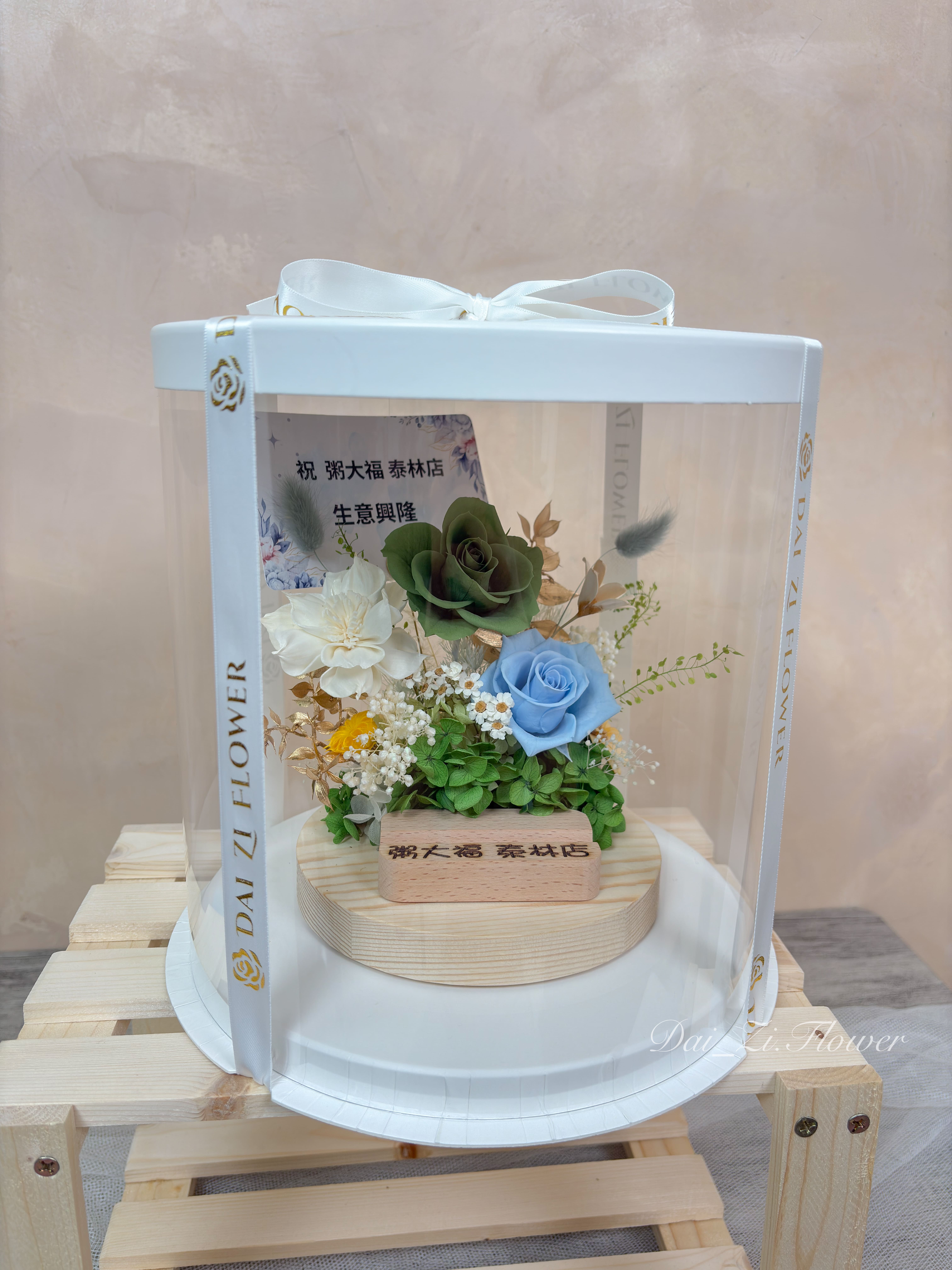 精品開幕送禮首選，DAIZI 代紫花藝專屬訂製之永生花名片座禮盒，以綠玫瑰點綴金葉呈現森林系高質感，大幅提升商業空間櫃檯佈置的專業度。