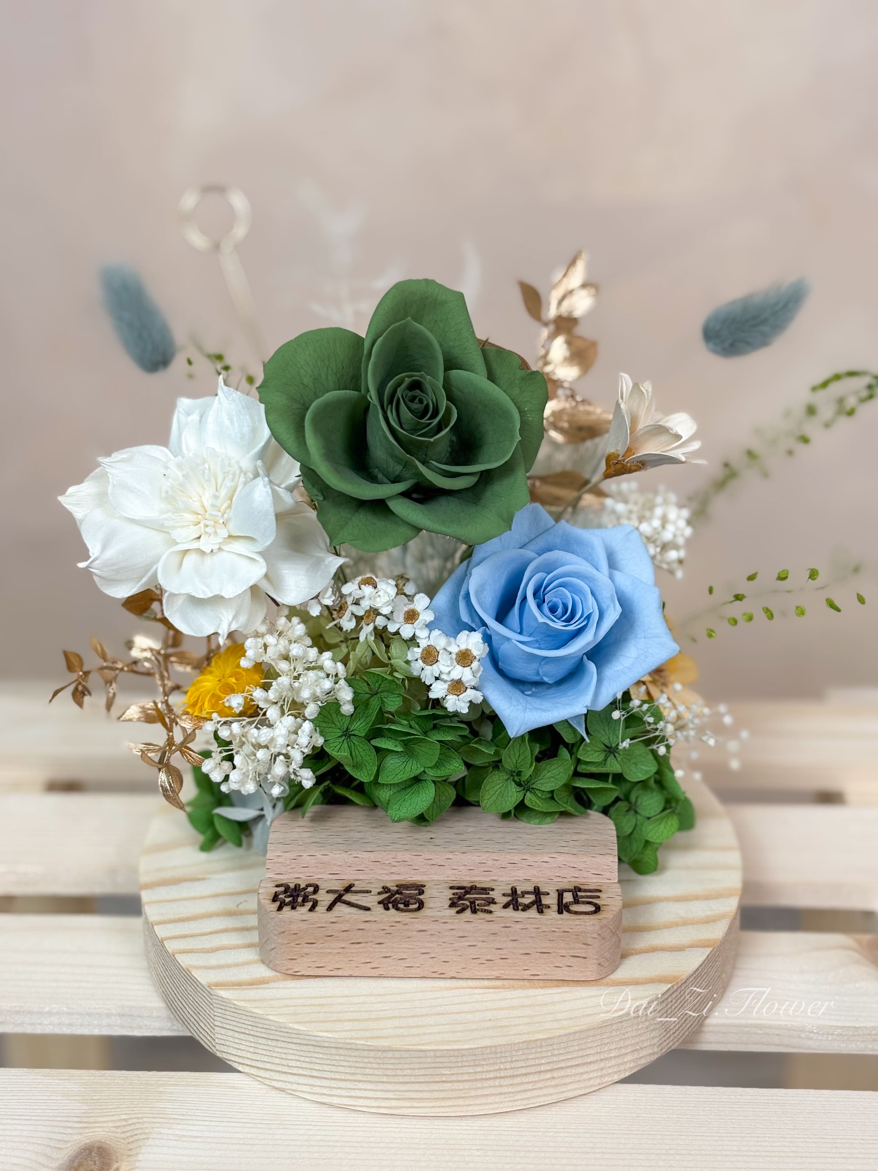 替代文字：DAIZI 代紫花藝為粥大福泰林店專屬訂製的永生花名片座，清新森林系綠玫瑰與藍玫瑰設計，是大台北地區熱門的精品開幕送禮與櫃檯佈置首選。