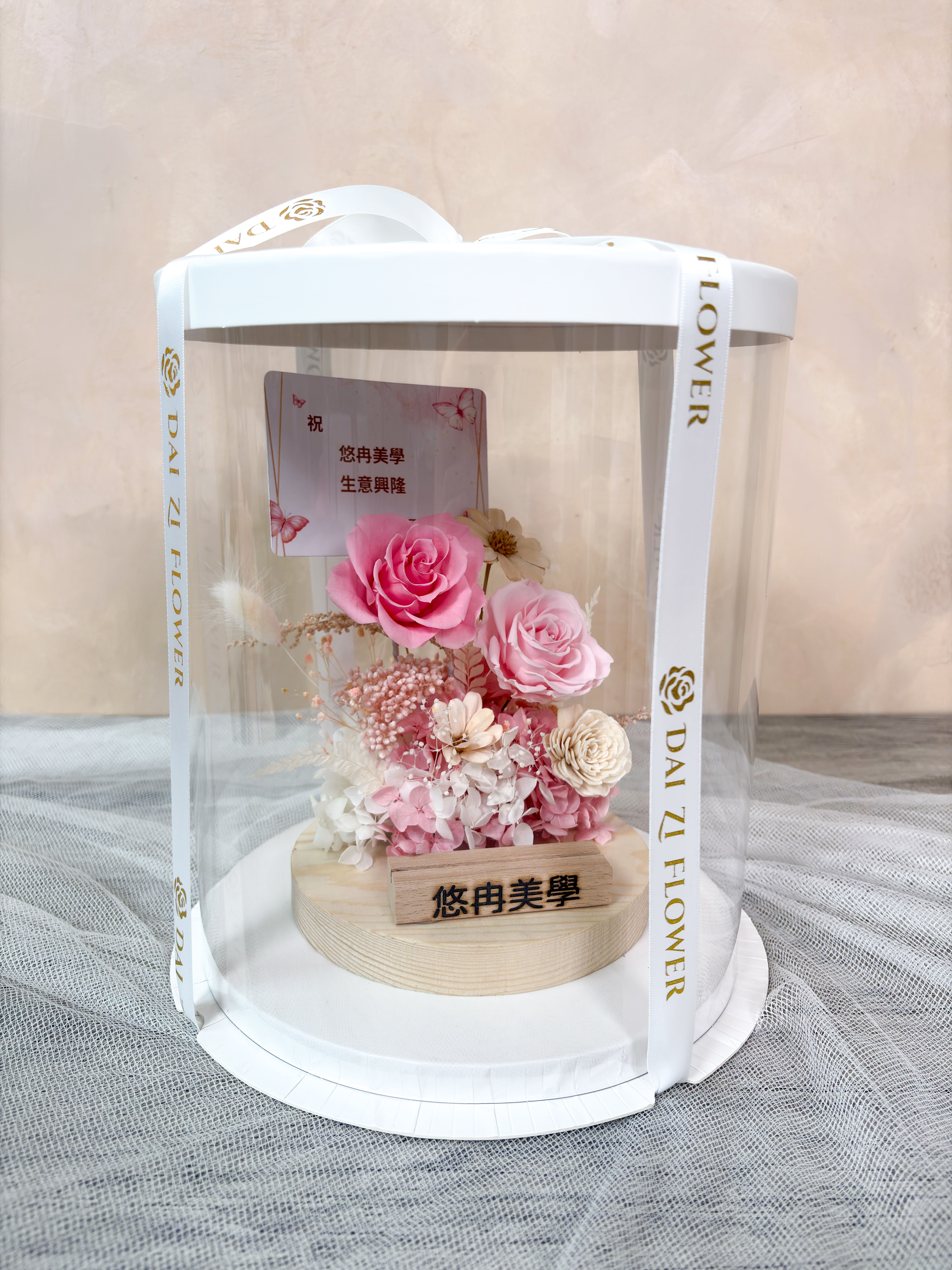 精品級開幕送禮推薦，代紫花藝客製化永生花名片座圓形透明禮盒包裝，展現極致體面的送禮質感，適合美甲、美睫工作室櫃檯佈置與開幕花禮。