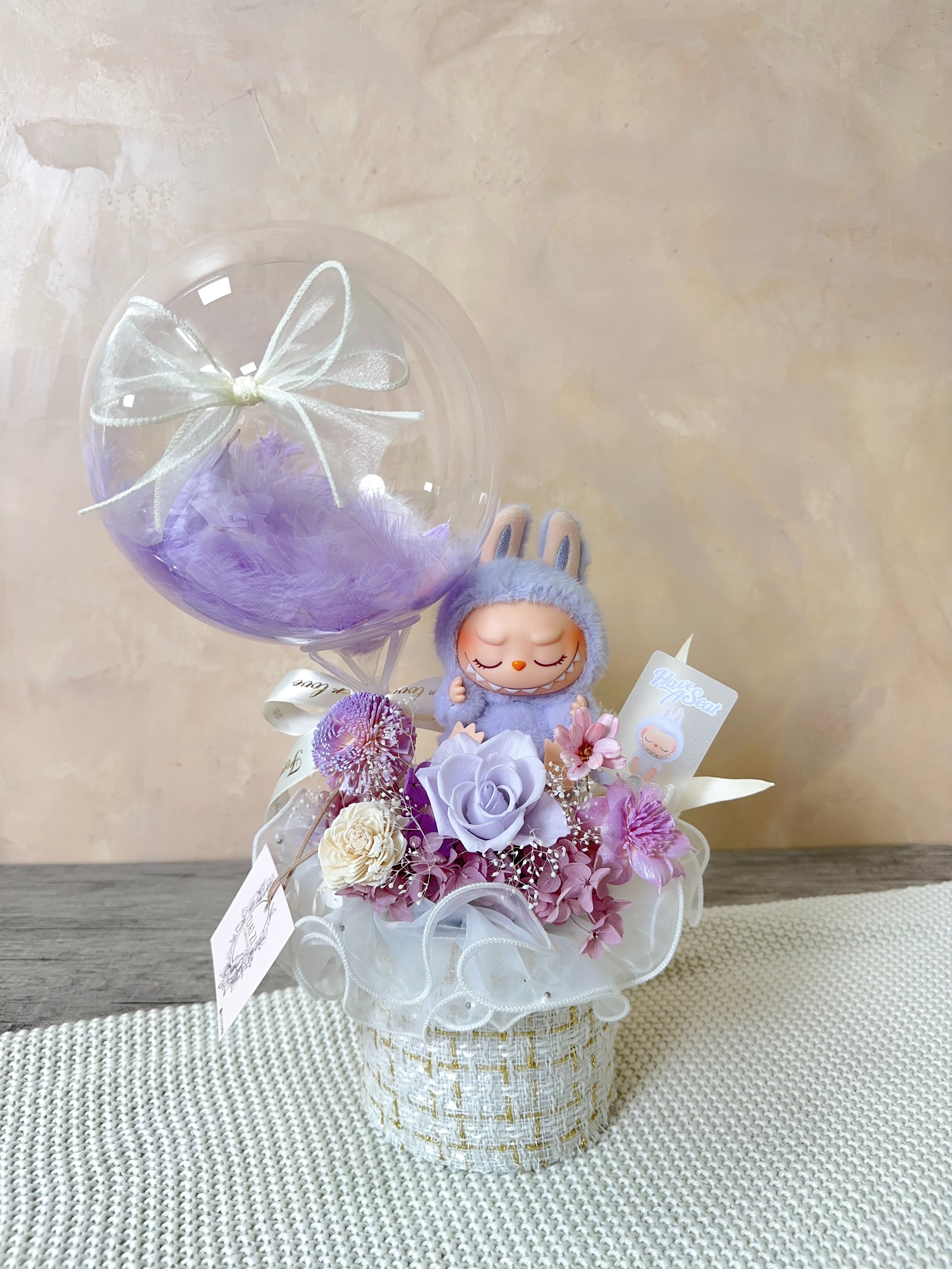 紫色永生玫瑰與LABUBU玩偶細節特寫，展現精品抱抱桶的設計層次與美學映像，台北中山區民權西路專業花店客製化服務。