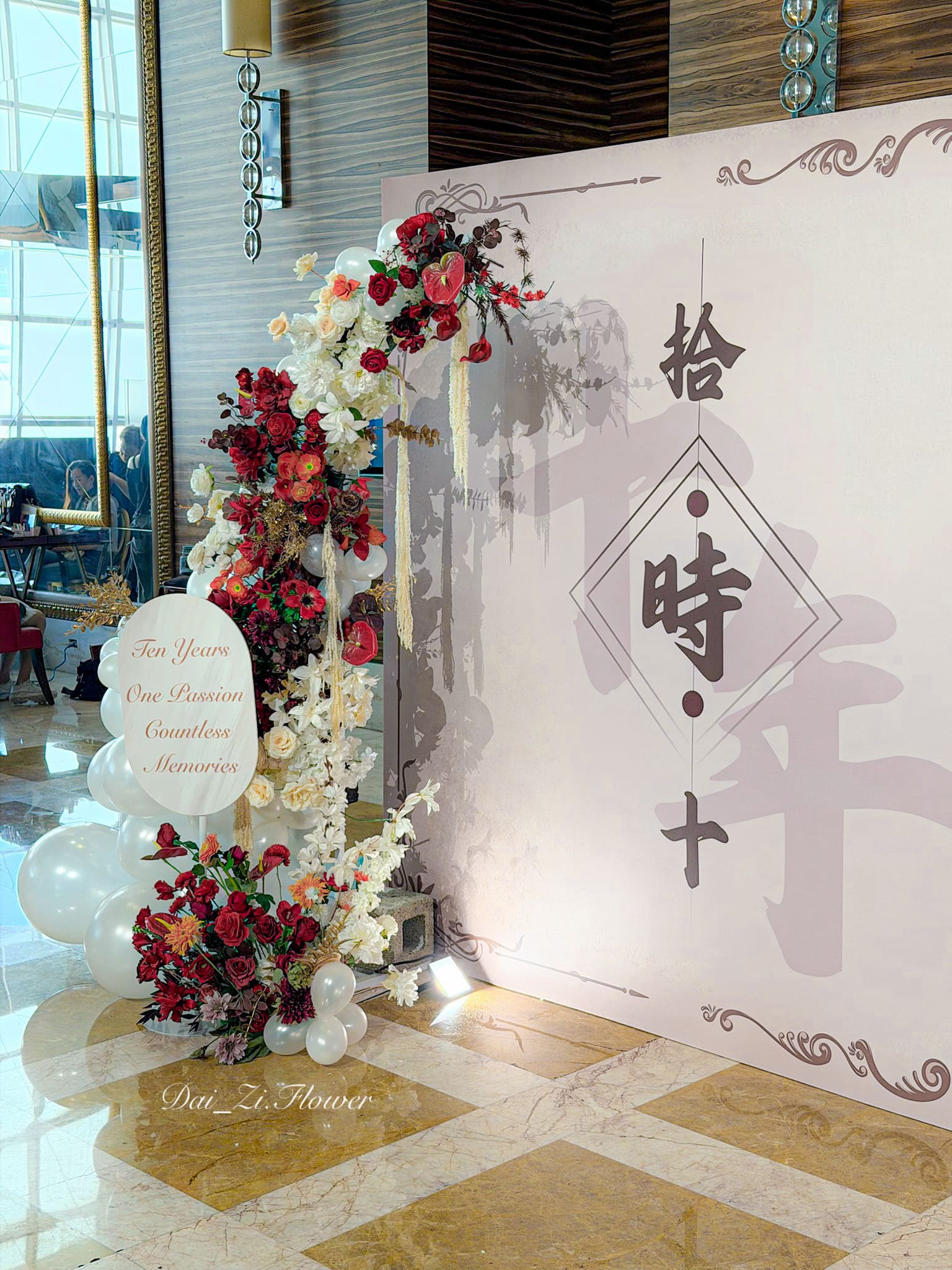 DaiZi 代紫花藝｜大直典華左側花藝立柱日光側拍—酒紅深紅橘白香檳色仿真玫瑰菊花滿版花藝柱搭配白色氣球底座與圓形客製文字牌，台北頂級宴會廳舞蹈發表花藝柱佈置推薦