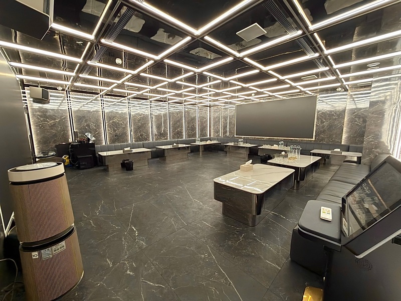 ROOM 9 T9 內湖招待所大包廂全景－深色大理石地板與牆面，格柵燈條天花板，環形灰色皮革沙發，超大LED主螢幕